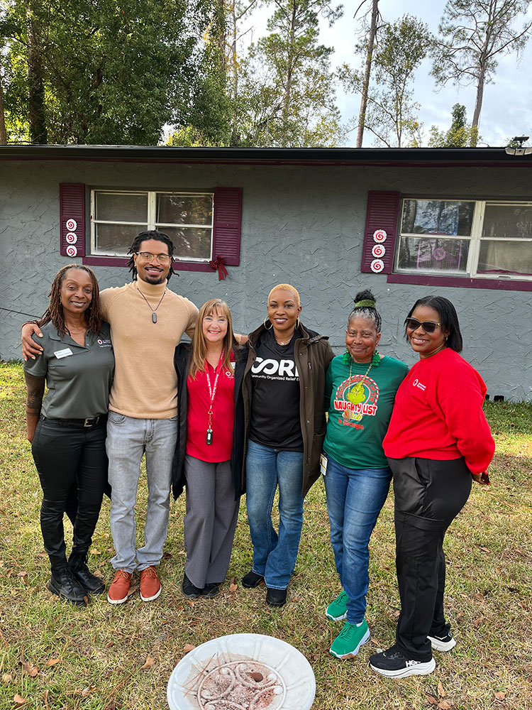 group photo of Edwina Gibson of the Red Cross, Jacque Ridore of CORE, Jackie Shoemaker of the Red Cross, Myrline Newton of CORE, homeowner Emma Holmes, and Dr. Affie Ben‑Edet of the Red Cross.