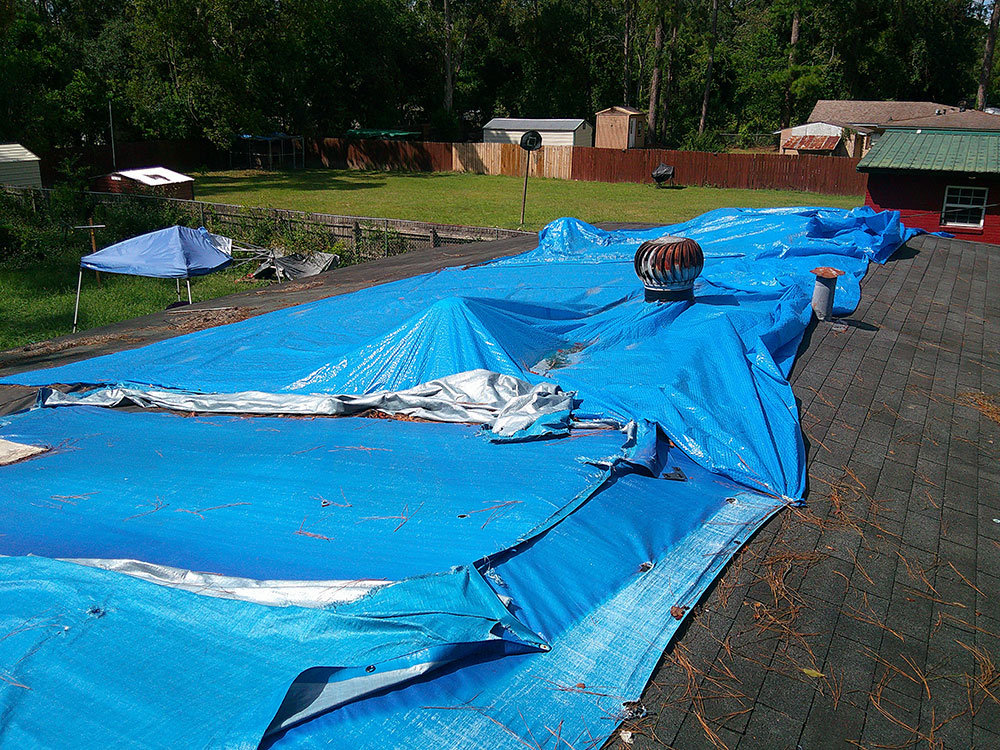 A large tarp covering the roof of a house.