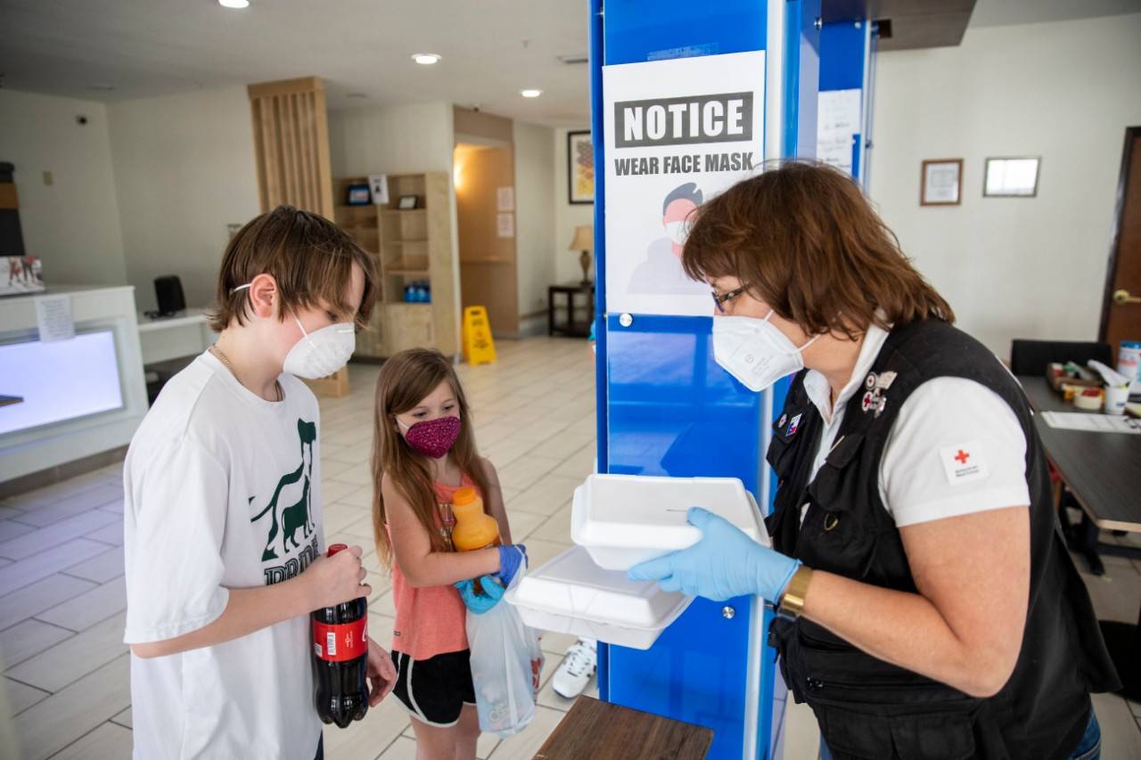 April 26, 2020. Livingston, Texas.
Clarruth Seaton of The American Red Cross hands a meal to Aaron and Chloe, 9 yrs old, at a hotel where the Red Cross is providing emergency lodging just a few miles from Onalaska, TX, the community that was hit by the powerful tornado on April 22, 2020, that damaged hundreds of homes.
Photo by Scott Dalton/American Red Cross