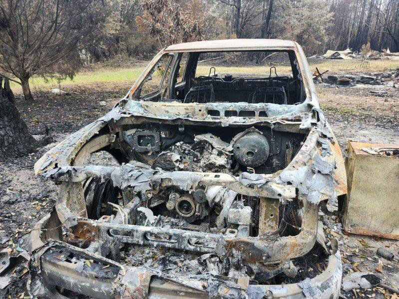 a burned down vehicle in a wooded area.