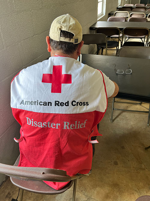 the back of a Red Cross shelter volunteer sitting down in a chair.