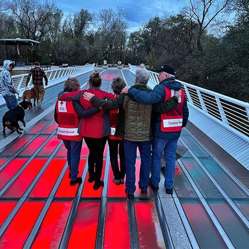 Red Cross volunteers on lit up red Sundial Bridge