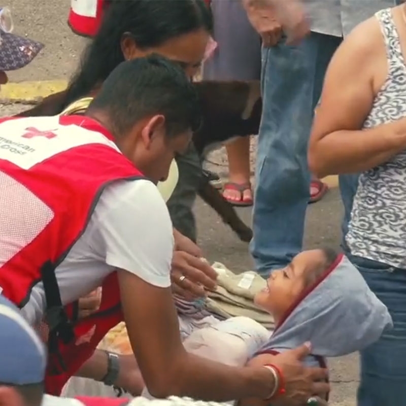 Red Cross volunteer helping little child