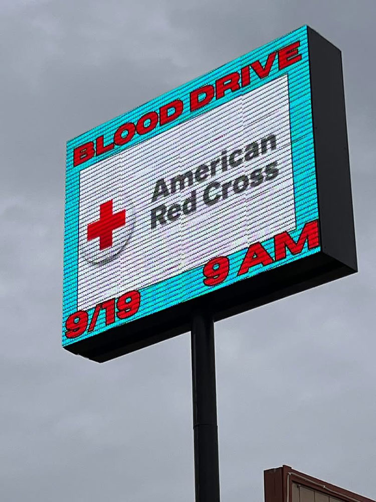 A lit up pylon sign with a Red Cross blood drive time and date.