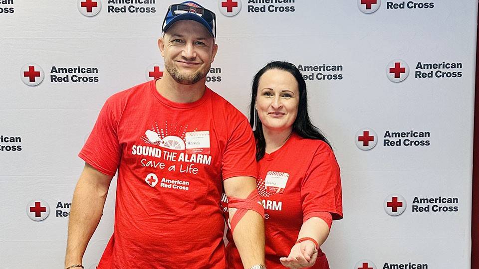 husband and wife show the bandages around their arm after donating blood.