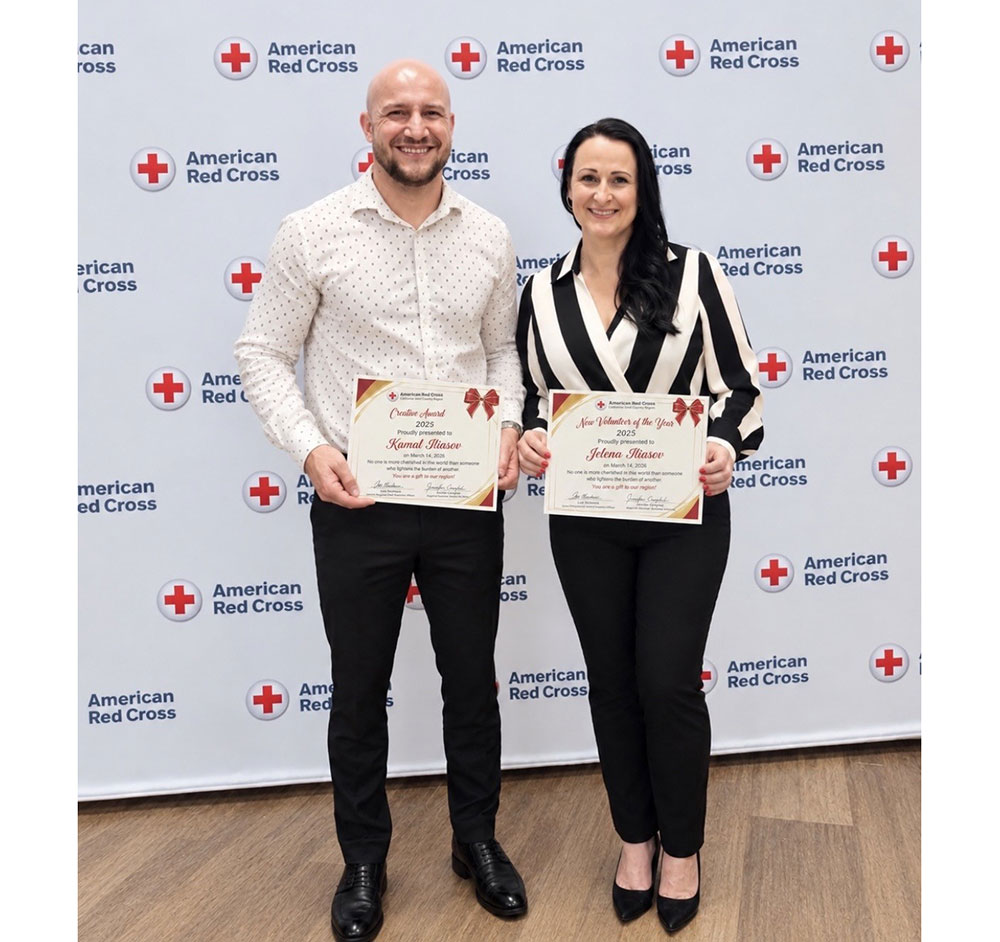 two Russian-speaking volunteers hold their Red Cross awards at a Red Cross event.