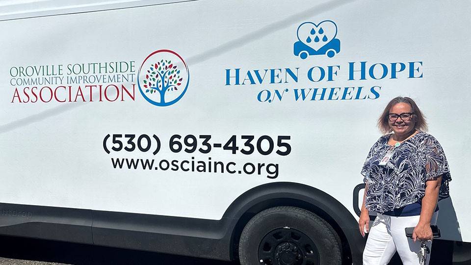 Lisa Torres standing next to the Haven of Hop on wheels van.