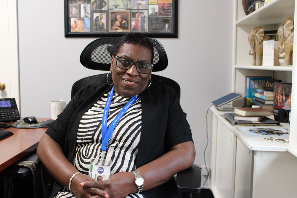 Dr. La Vetta Coleman sitting in an office chair at a desk and smiling.