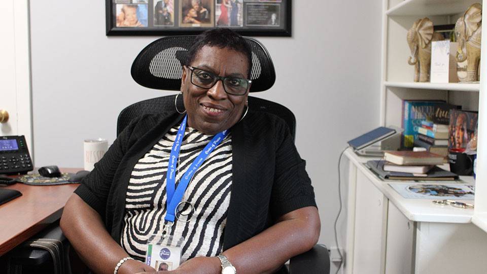 Dr. La Vetta Coleman sitting in an office chair at a desk and smiling.