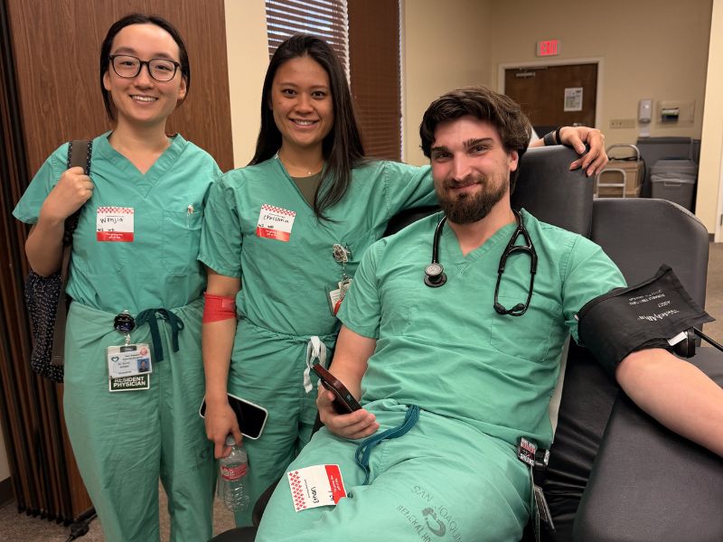 nurses gathered together as one rolls up sleeve for blood donation