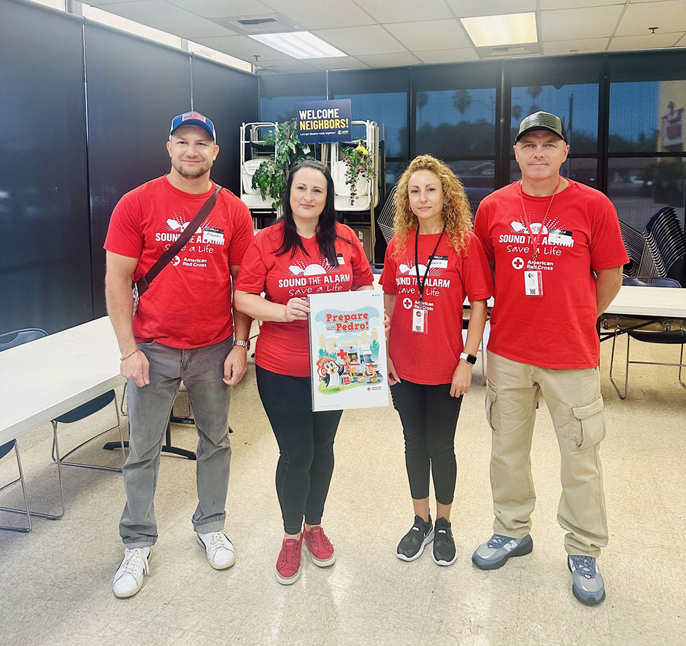four Russian-speaking volunteers with one of them holding a Prepare with Pedro! book.