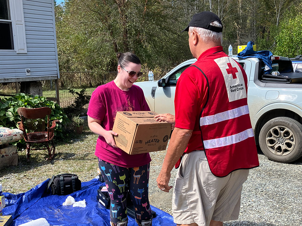 Red Cross volunteer handing box to resident affected by hurricane.