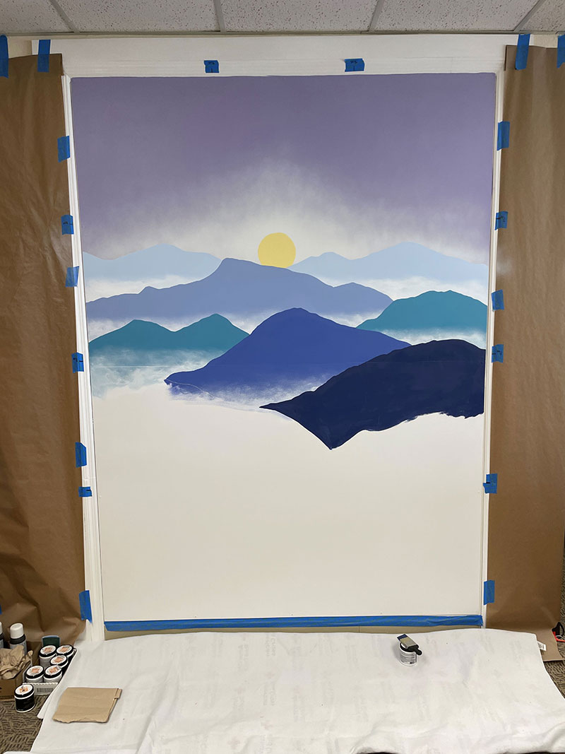Half painted mural of sunrise and mountains.