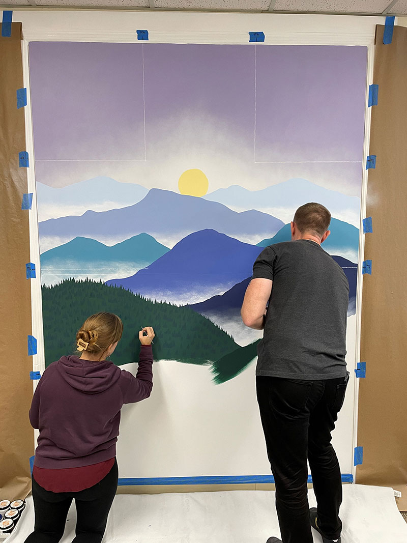 Two people painting a mural.