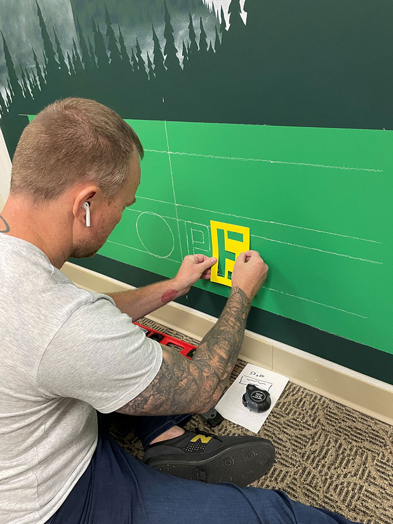 Person adding letters to a mural.