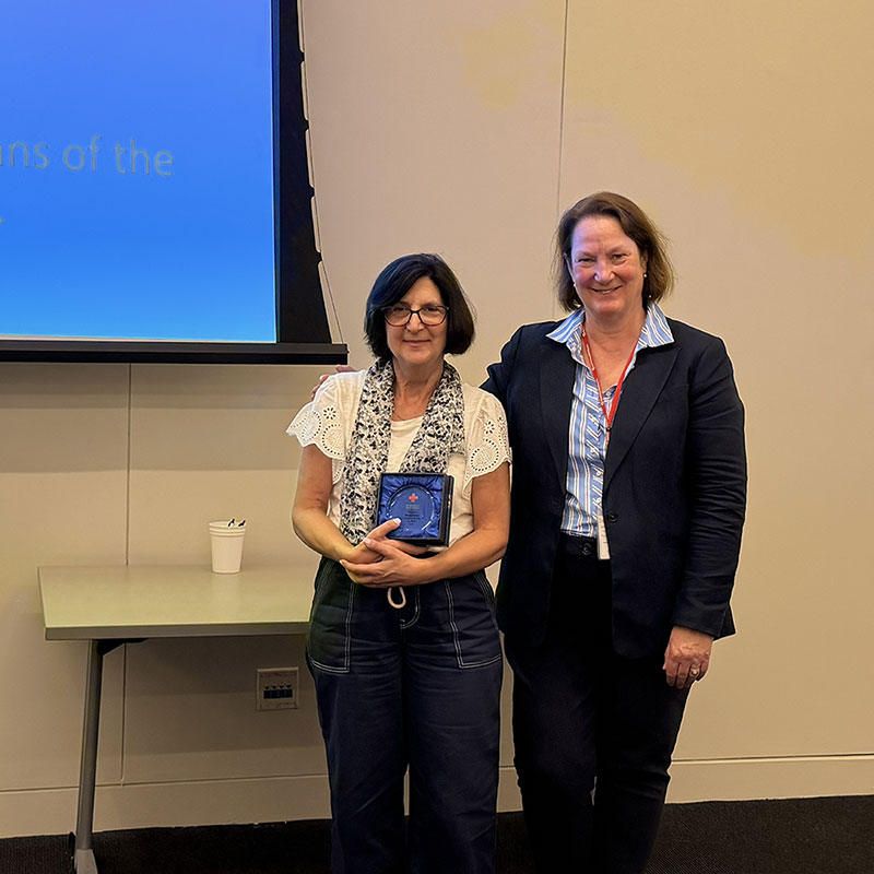 Denise Bloise holding a 5c award next to a Red Cross staff member at a Red Cross event.