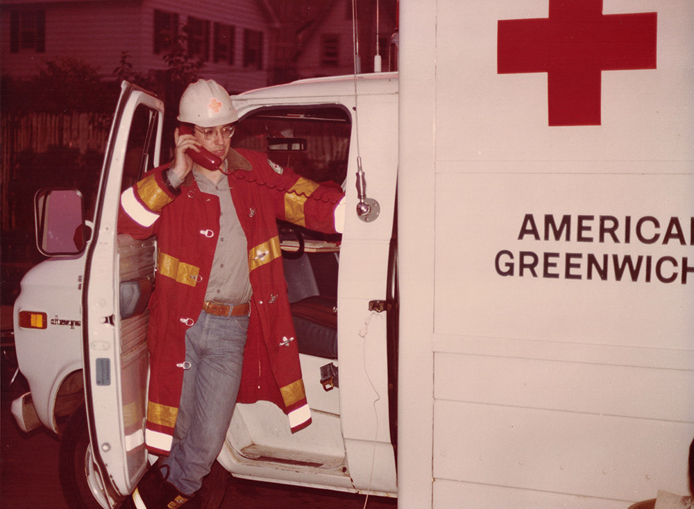 Red Cross volunteer stands in the doorway of a Red Cross disaster response truck.