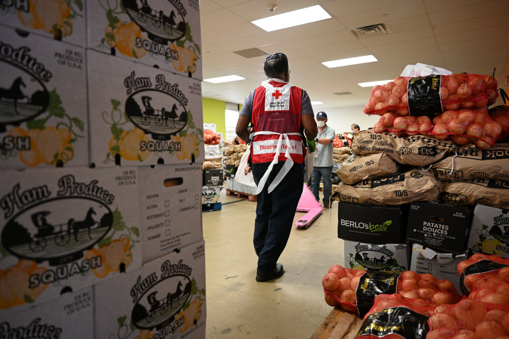The back of a Red Cross volunteer in a room filled with food.