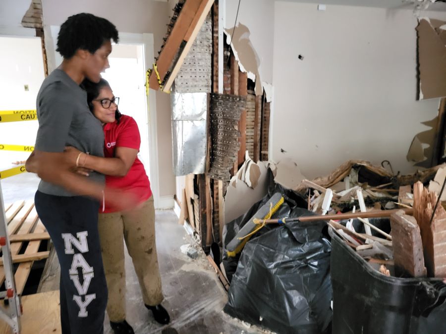 Red Cross Hero Care Network caseworker Lallita Maharaj embraces Martha Richardson as they look at the destroyed remains of Richardson's home