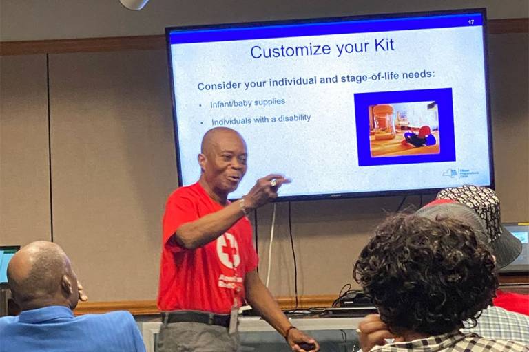 Red Cross volunteer teach class with tv in background