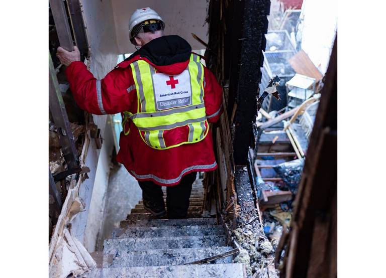 Red Cross volunteer walking through burnt building