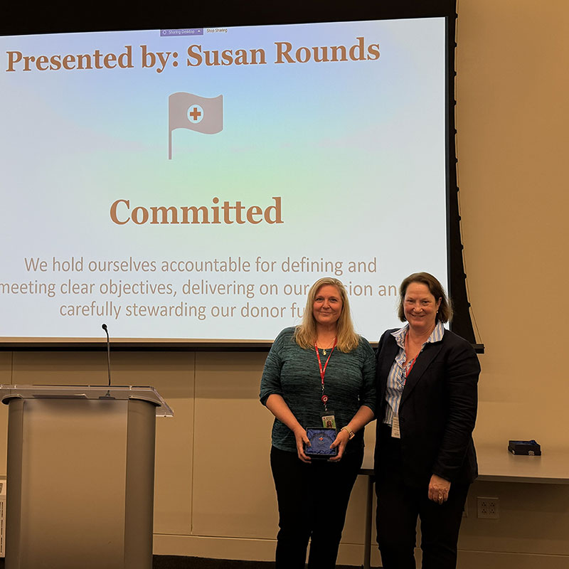 Karen Stichauner holding a 5c award next to a Red Cross staff member at a Red Cross event.