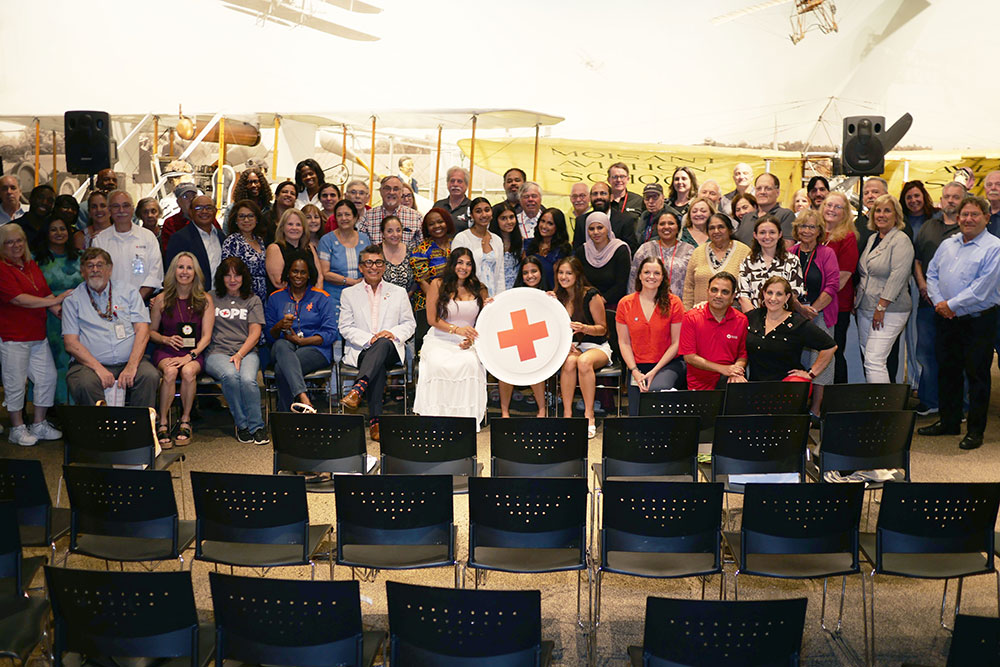 Group photo of the Long Island Chapter staff with three members holding a large Red Cross logo.