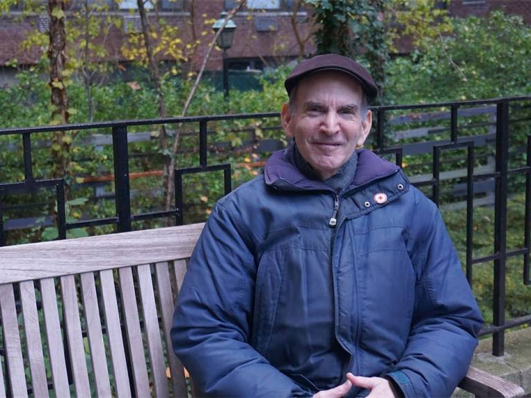 Richard Gallis sits in the courtyard of his apartment.