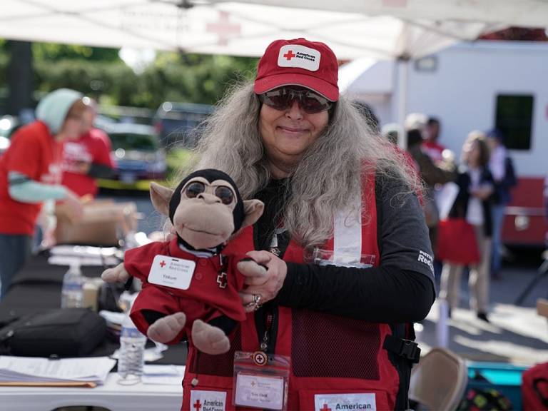 Tess Sheil poses with Yokum, a stuffed monkey that frequently deployed alongside Tess for the Red Cross.