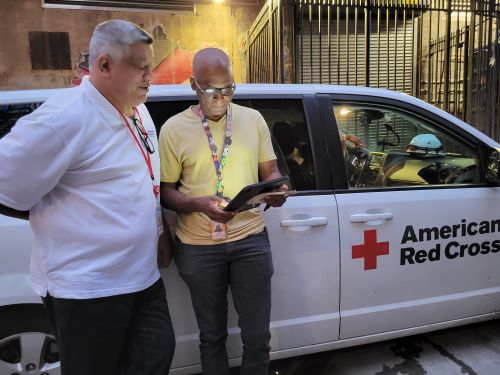 Disaster Action Team (DAT) volunteers Julio Medina (left) and Glendoval Stephens (right) look over a client intake form on their tablet after a vacate order was issued in the Bronx
