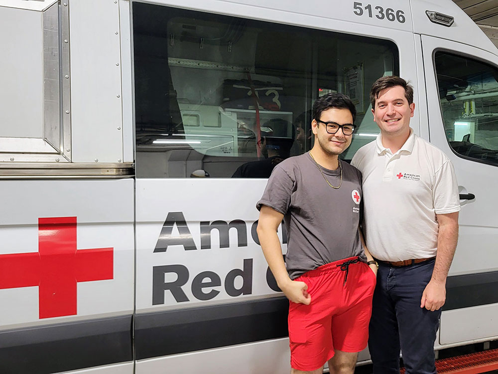 Red Cross volunteers Sasha Simmons and Brandon Sherr, wearing Red Cross shirts, stand next to an Emergency Response Vehicle