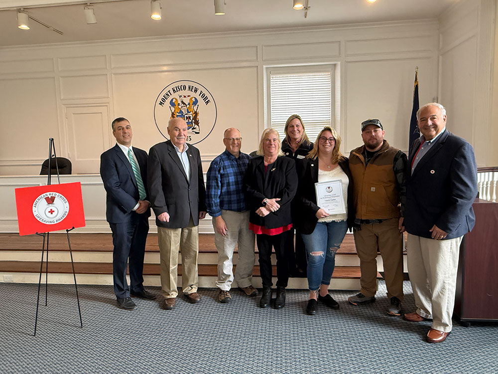 Valerie Kaplan displaying her Lifesaving Award with Red Cross staff members.