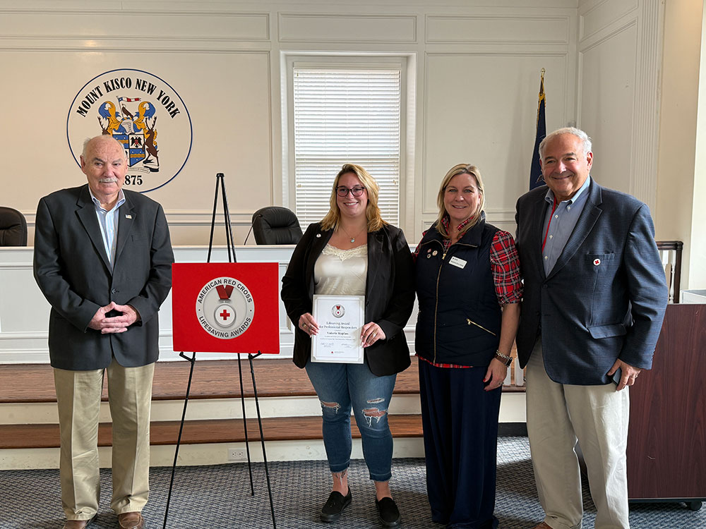 Valerie Kaplan displaying her Lifesaving Award with Red Cross staff members.