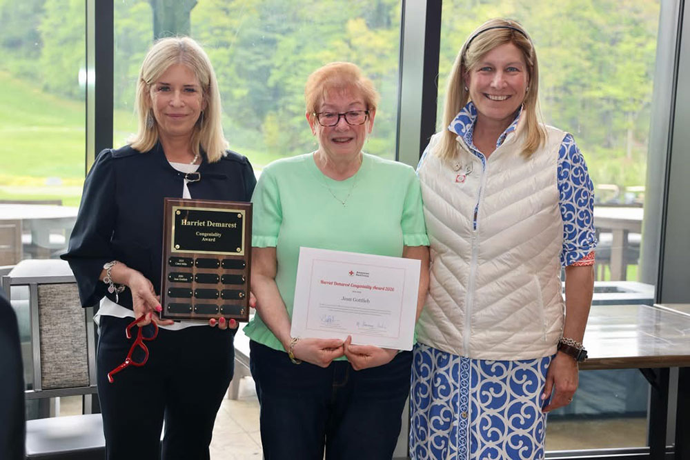 Red Cross volunteers hold their awards next to a Red Cross staff member.