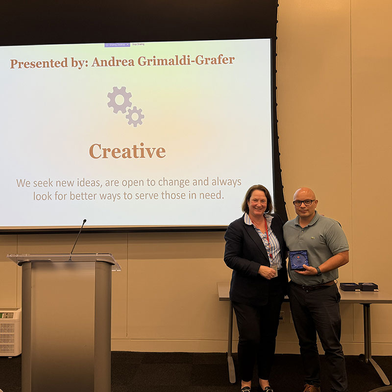 Mauricio Serrato holding a 5c award next to a Red Cross staff member at a Red Cross event.