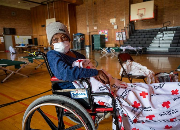 Woman in wheelchair with Red Cross blanket