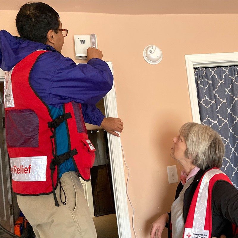 Martin Ramos and Susan West install a strobe light smoke alarm