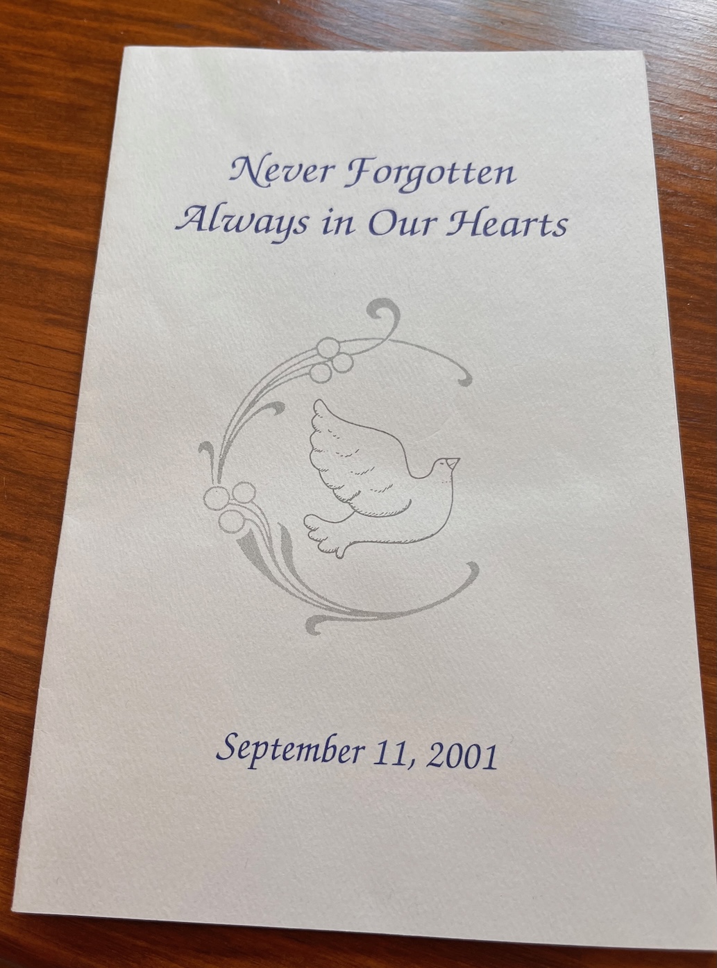 Cover of a program with the text, "Never Forgotton, Always in Our Hearts, September 11, 2001) and an image of dove
