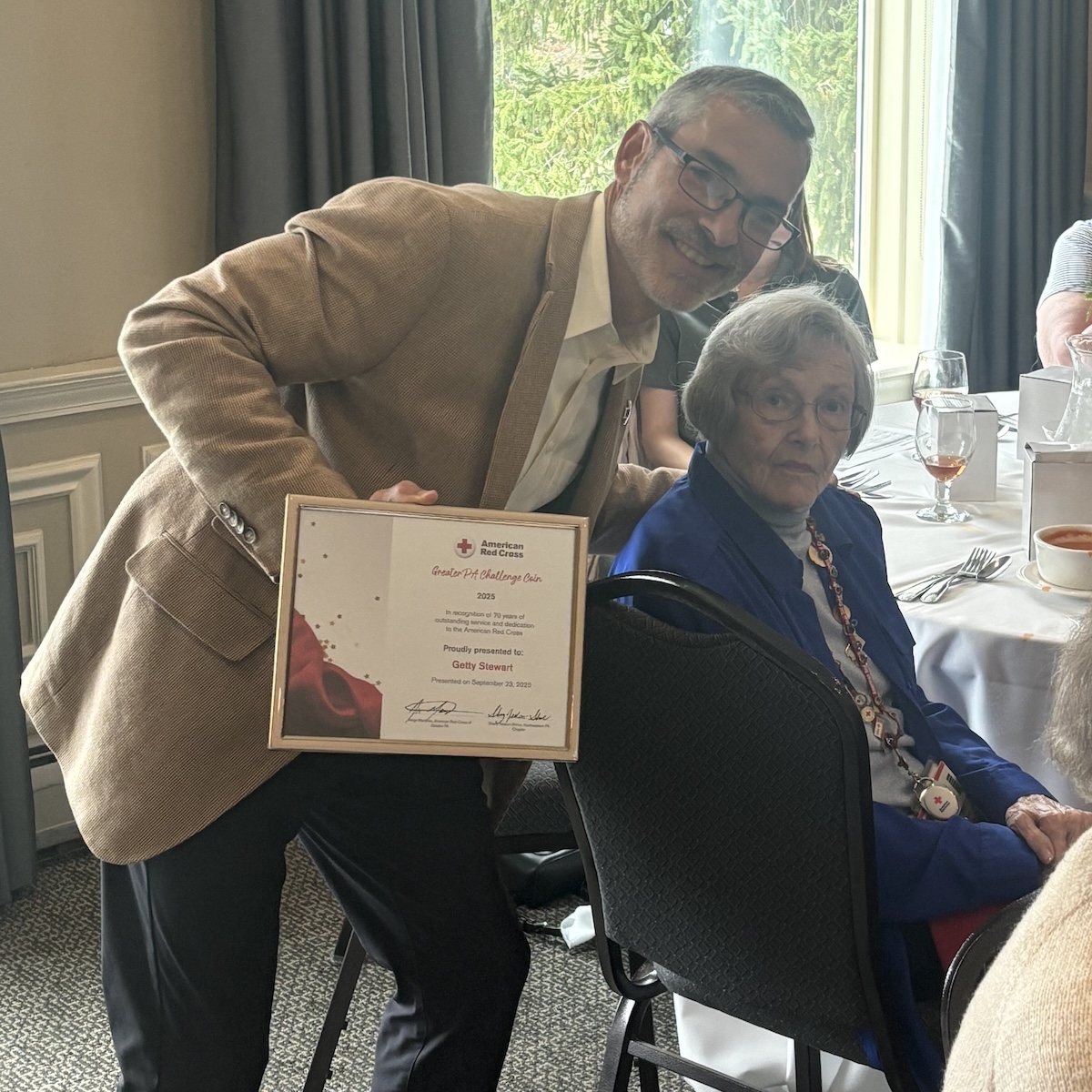 Jorge Martinez, CEO of the American Red Cross of Greater Pennsylvania, smiles with Getty Stewart after presenting an award.