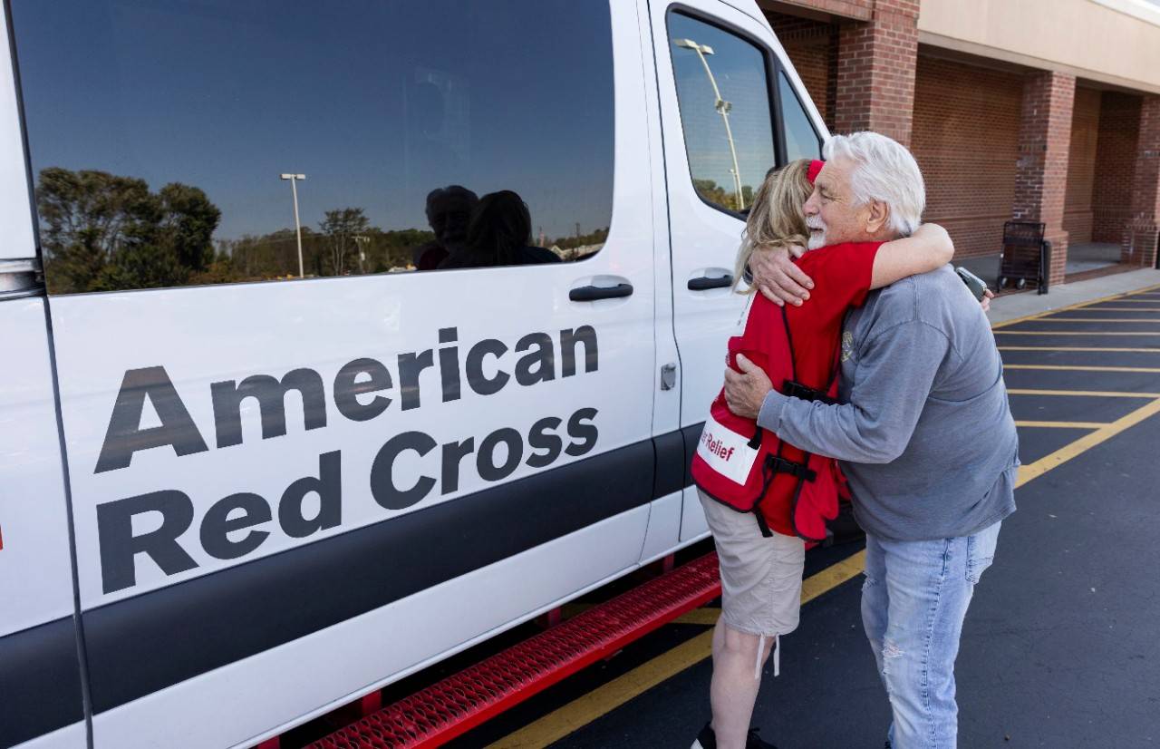 October 8, 2024.  Weaverville, North Carolina.
American Red Cross volunteer Linda Kerner shared an embrace with Gary Howell outside Ingles Market in Weaverville, North Carolina. Gary stopped by the location to pick up a hot meal while he works to recover from the devastation left by Hurricane Helene. The Red Cross has been working tirelessly with dozens of partners to get urgent shelter, food, water and comfort to those affected by Helene. Helene s destruction covers a huge area. The Red Cross is working with local officials, government agencies and other nonprofits. Dozens of emergency response vehicles have been on the roads providing meals, water and supplies to those living without electricity and struggling to clean up their homes. Hundreds of Red Crossers and our partners have provided overnight stays in emergency shelters, meals and snacks to help those affected by Helene.
Photo by Scott Dalton/American Red Cross

