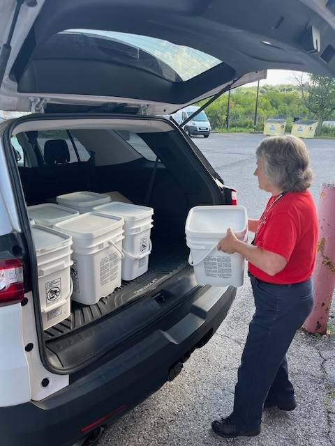 Volunteer Peggy Wilkins loads buckets into a car