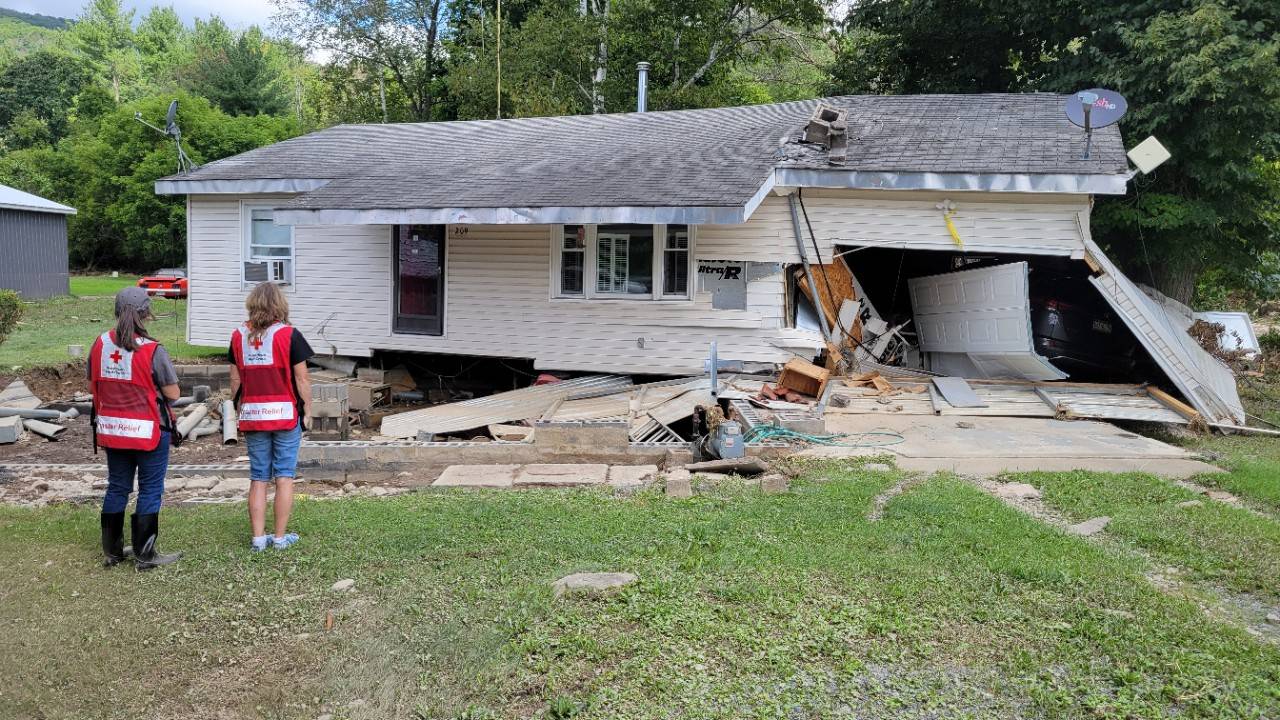 Volunteers stand in front of a damage house 