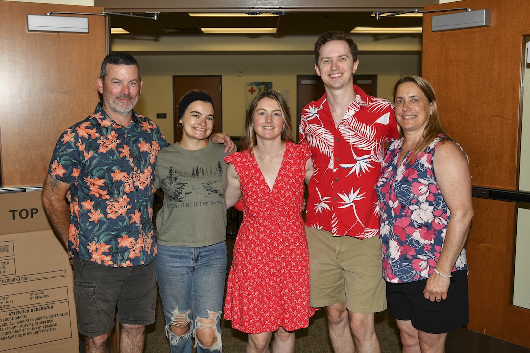 Kylie McCullough poses with four adults, smiling, with blood drive in the background