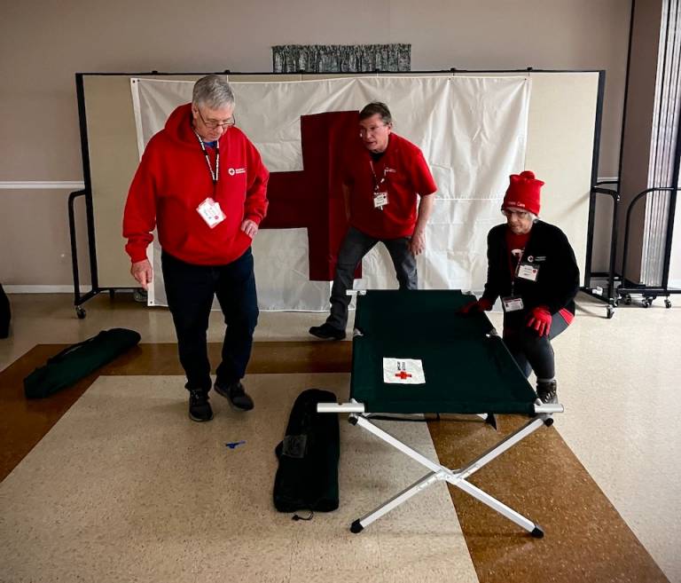 Red Cross volunteers practice setting up cots in emergency shelter