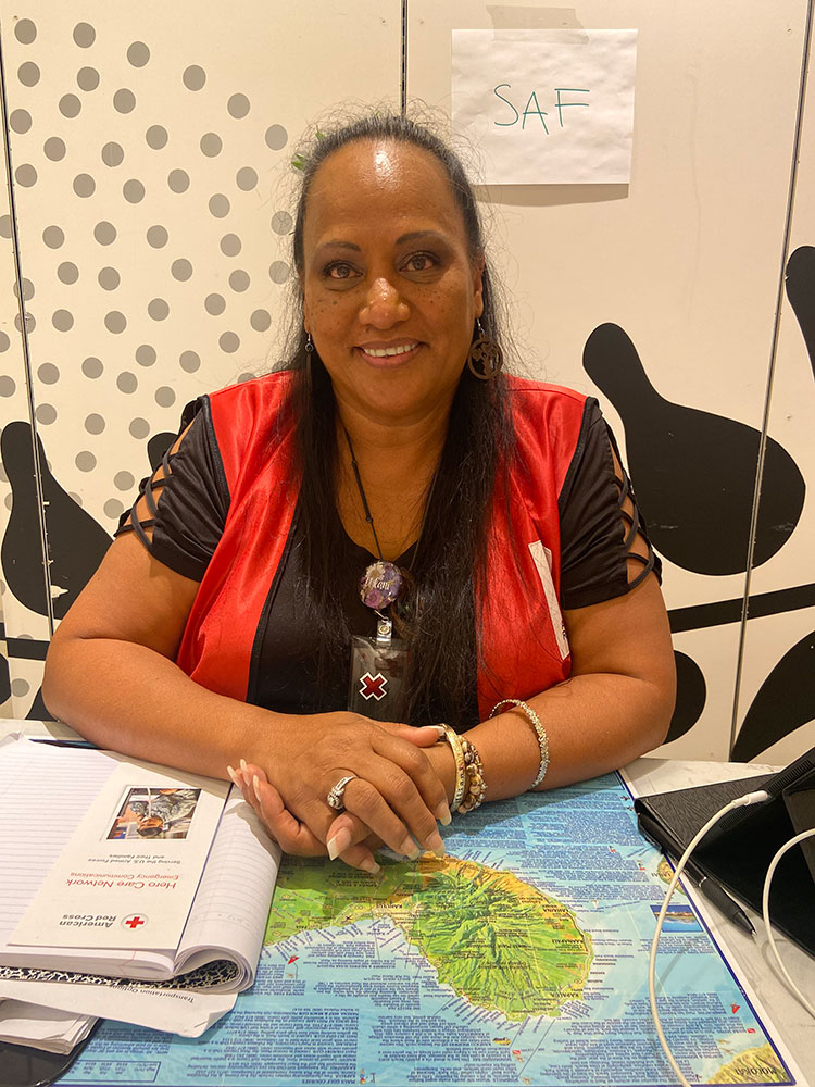 Red Cross volunteer sitting down with map and books on the table.