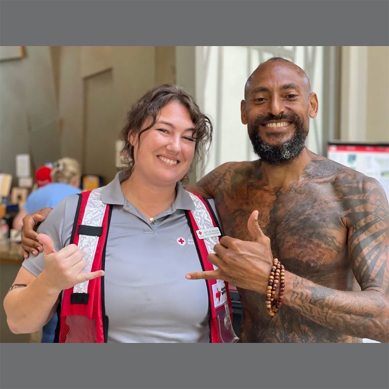 Red Cross volunteer with man she helped smiling for camera.