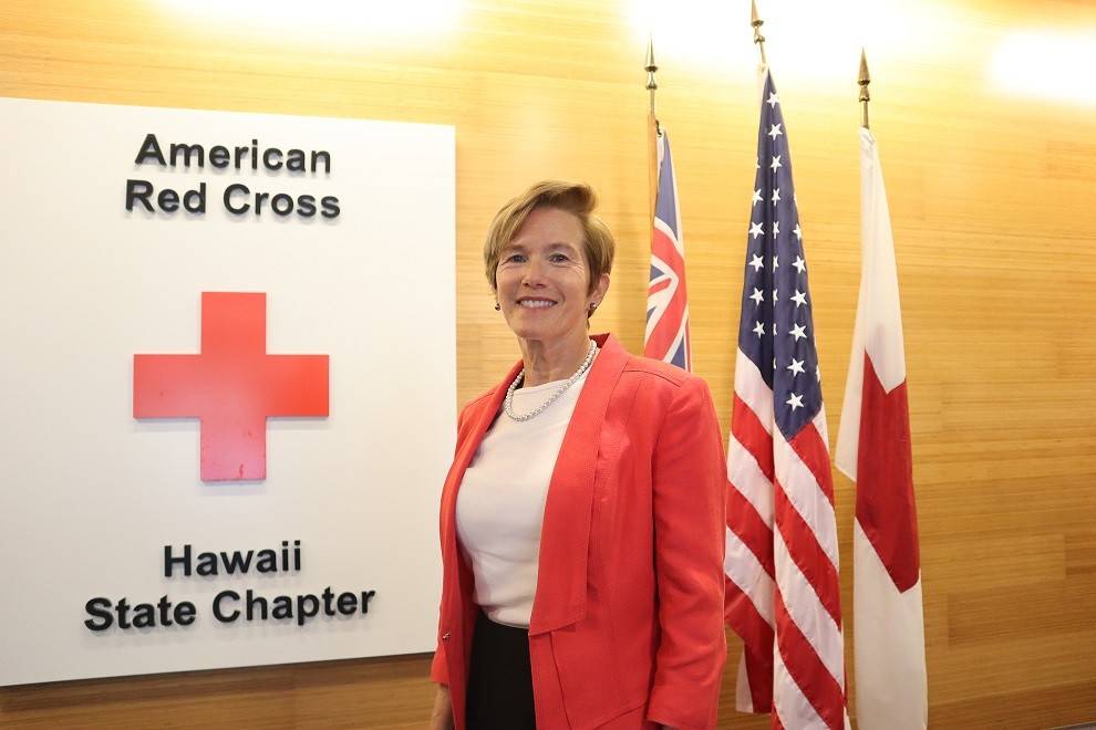 Diane Peters-Nguyen in front of Red Cross of Hawaii seal.
