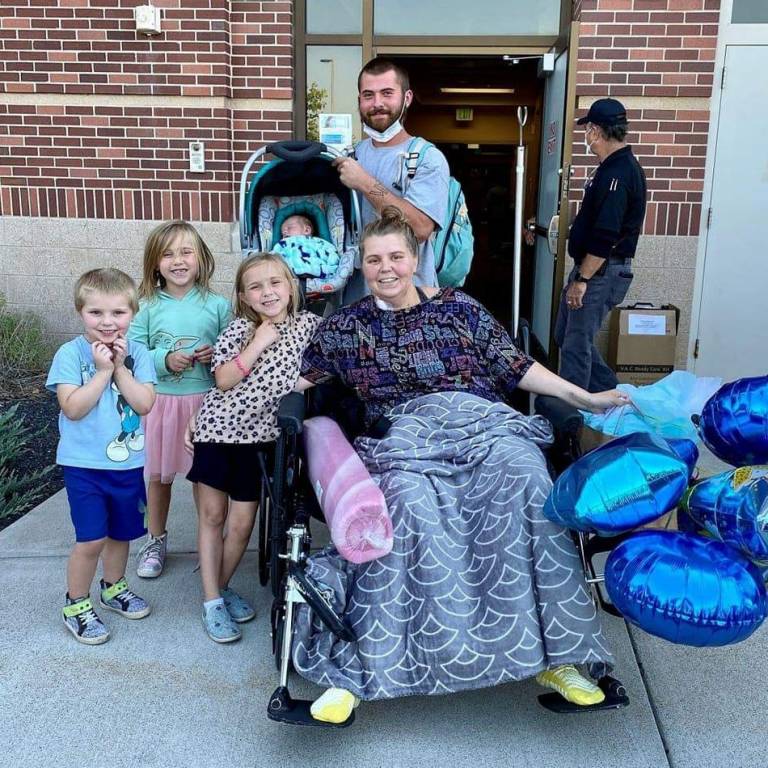 Shandra Sterner in a wheelchair surrounded by her family outside of a hospital.