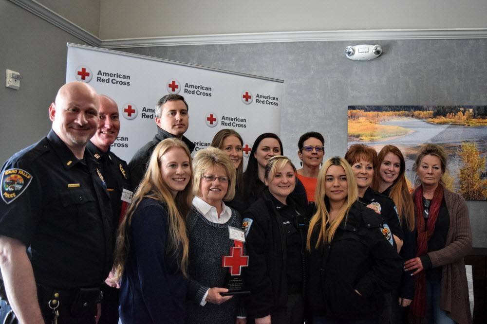 Group of men and women standing in front of an American Red Cross screen