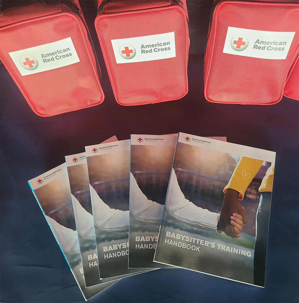 American Red Cross bags and a stack of babysitter's training handbooks.